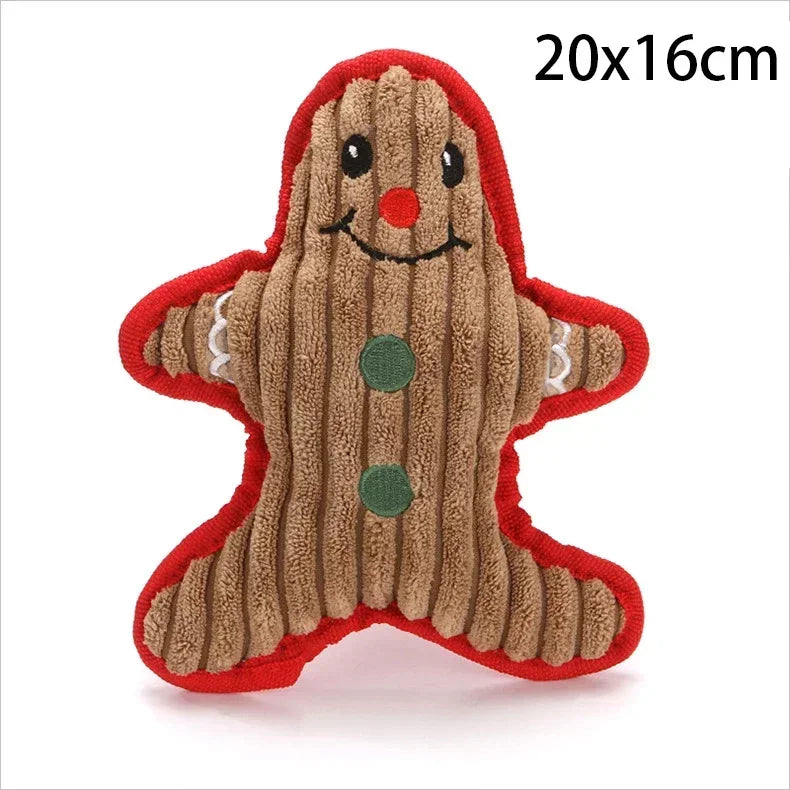 A gingerbread man plush dog toy made of brown textured fabric with red trim, black embroidered eyes and mouth, a red nose, and green buttons. 